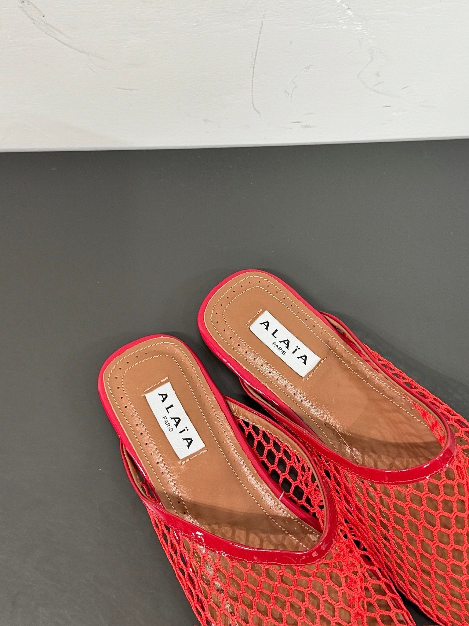 ALAIA FLAT MULES IN CHERRY RED MESH FISHNET